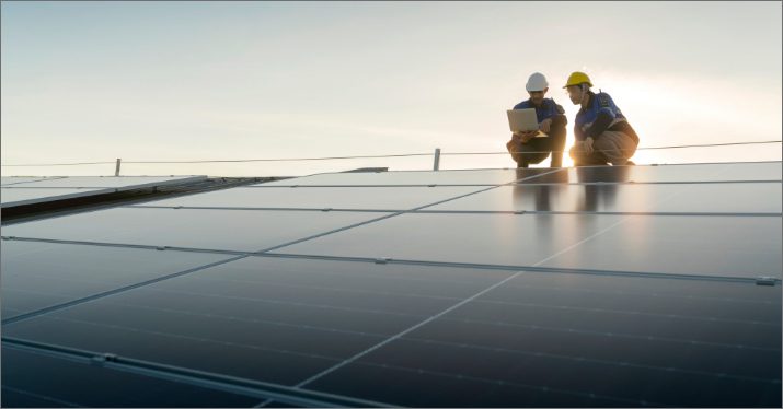two workers inspecting solar panels on a roof